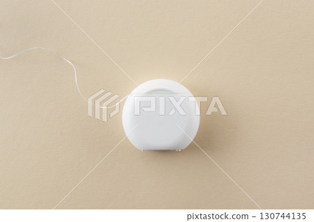 White dental floss for mouth hygiene and health teeth on beige background with space for text. White dental floss for mouth hygiene and health teeth on beige background with space for text. 130744135