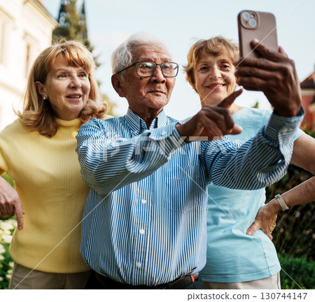 Joyful older adults happily taking a fun selfie together in a beautiful autumn park setting 130744147