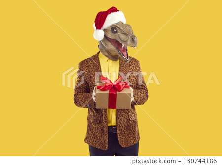 Eccentric man in dinosaur head mask with gift box 130744186