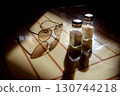 Glasses, pepper shaker and salt shaker on the table in backlight 130744218