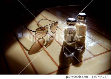 Glasses, pepper shaker and salt shaker on the table in backlight Glasses, pepper shaker and salt shaker on the table in backlight 130744218