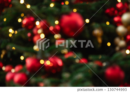 Blurred Christmas tree with garland and red balls. Abstract pattern. Defocused background. Xmas holiday spirit. 130744993