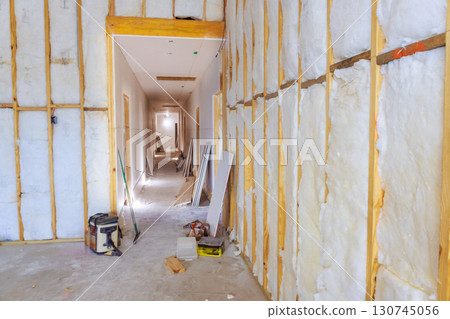 Insulation is being installed in hallway of residential building during construction activities. 130745056