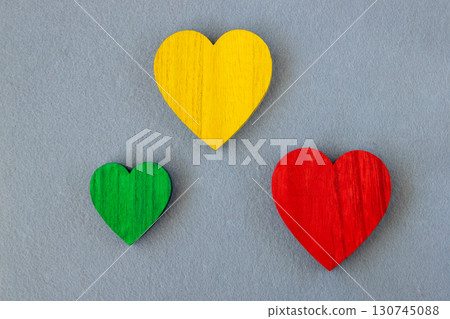 Traffic light colors. Green, red, yellow wood hearts on the gray fabric background. Romantic greeting card.  130745088