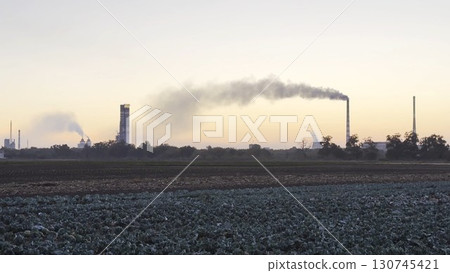 Heavy gray smoke is poured from the chimney pipes of thermal power plant. Carbon dioxide emitting from chimneys from industrial factory into the atmosphere. Concept of environmental pollution problem Heavy gray smoke is poured from the chimney pipes of thermal power plant. Carbon dioxide emitting from chimneys from industrial factory into the atmosphere. Concept of environmental pollution problem 130745421