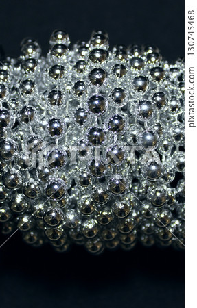 Shiny balls of a long beads are wound on a roll closeup stock photo 130745468