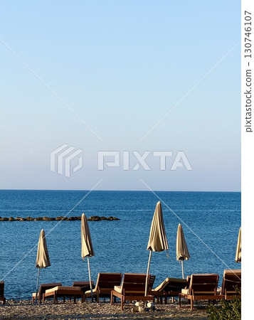 Public beach, summer, beautiful sunny weather. Picturesque beach, waves crashing on the sandy shore. Sea waves beat against the rocks. Cyprus Island, umbrellas, tourist boats, Mediterranean Sea. Public beach, summer, beautiful sunny weather. Picturesque beach, waves crashing on the sandy shore. Sea waves beat against the rocks. Cyprus Island, umbrellas, tourist boats, Mediterranean Sea. 130746107