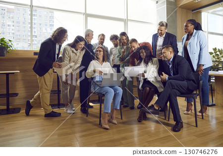 Female employee showing something to his colleagues on laptop in meeting room in office. 130746276