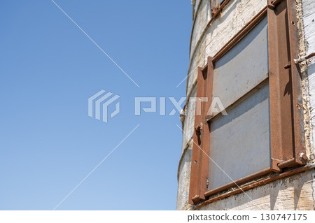 Rusty window on an old silo against a clear blue sky showcases the passage of time in rural america Rusty window on an old silo against a clear blue sky showcases the passage of time in rural america 130747175