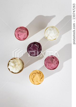 Assorted colorful soft serve ice cream in paper cups on white background, top view 130747263
