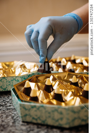 Placing premium handmade chocolates into elegant golden packaging, close up view Placing premium handmade chocolates into elegant golden packaging, close up view 130747284