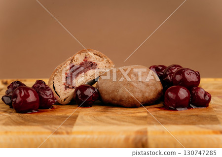 Chocolate cherry mochi dessert with juicy whole cherries on wooden board, studio shot 130747285
