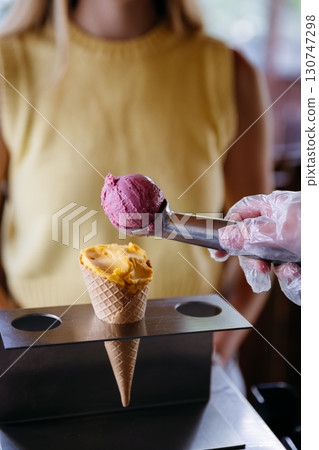 Colorful gelato scoop served in cone by vendor in gloves, summer dessert concept 130747298