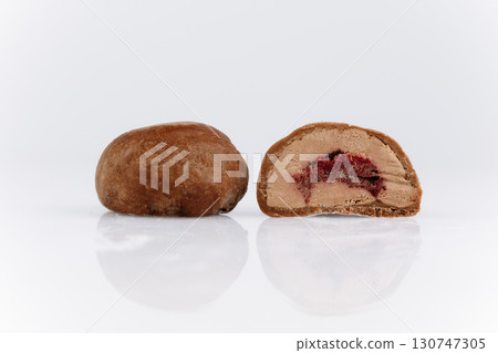 Chocolate covered mochi with cherry filling, cut in half on white background 130747305
