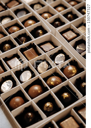 Luxury artisan chocolate bonbons with golden finish in elegant white gift boxes Luxury artisan chocolate bonbons with golden finish in elegant white gift boxes 130747327