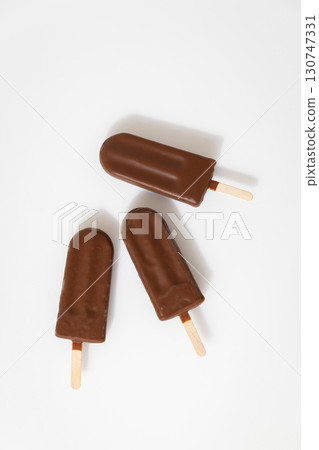 Chocolate ice cream popsicles on white background. Minimalist summer dessert concept Chocolate ice cream popsicles on white background. Minimalist summer dessert concept 130747331