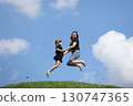 Mother and daughter happily jumping outside in summer 130747365