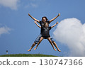 Mother and daughter happily jumping outside in summer 130747366