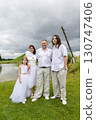 Family posing outdoors in white 130747406