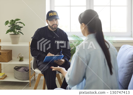 Police officer in uniform talking to worried woman witness, taking notes and investigating crime. Police officer in uniform talking to worried woman witness, taking notes and investigating crime. 130747413