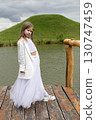 Little girl in a white festive dress in nature 130747459