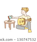A girl practicing guitar while looking at sheet music on a tablet 130747532