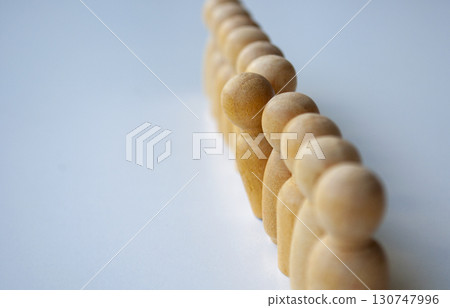 A series of beige wooden dolls aligned in a line with one of them stood out among them highlighting individuality or difference. A series of beige wooden dolls aligned in a line with one of them stood out among them highlighting individuality or difference. 130747996
