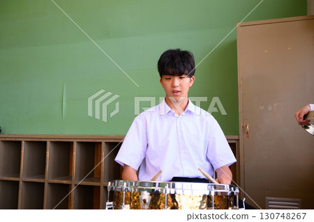Male student playing drums in the classroom Image of school life and musical activities Male student playing drums in the classroom Image of school life and musical activities 130748267