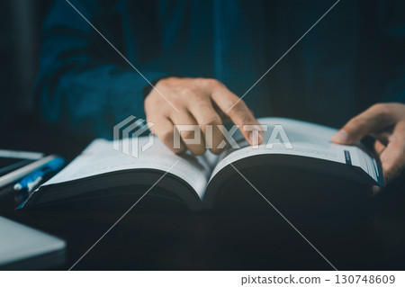 Man is sitting at the table and reading a book, close up, old style. Hand open book for reading. Man is flipping the pages of a book. Learning concept. Teacher. Man is sitting at the table and reading a book, close up, old style. Hand open book for reading. Man is flipping the pages of a book. Learning concept. Teacher. 130748609