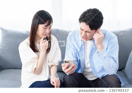 Men and women looking at smartphones with troubled expressions 130749337