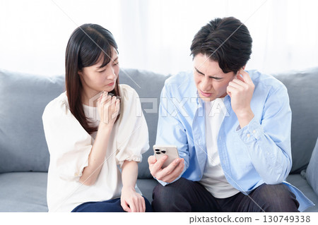 Men and women looking at smartphones with troubled expressions Men and women looking at smartphones with troubled expressions 130749338