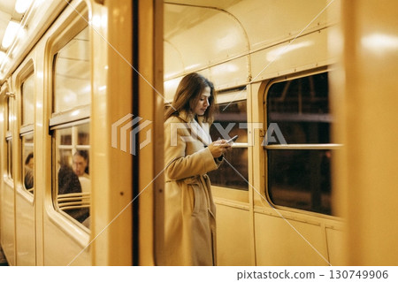 A woman standing on a train holding her phone. A woman standing on a train holding her phone. 130749906