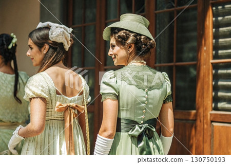 Women in Green Regency-Era Dresses Walking Together. 130750193