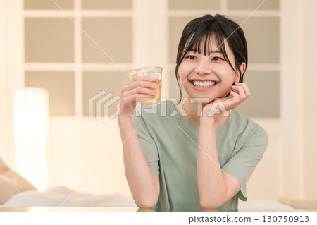 A young Asian woman having a drink in her bedroom at home (drinking at home, tipsy, drinking at home, drinking) 130750913