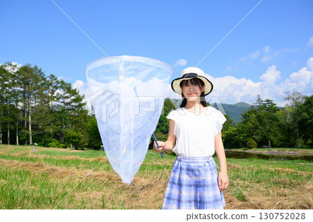 A girl enjoying catching insects under the blue sky 130752028