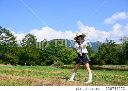 A girl enjoying catching insects under the blue sky 130752252