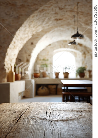 Rustic Mediterranean stone interior with wooden table and warm vintage lighting Rustic Mediterranean stone interior with wooden table and warm vintage lighting 130753606