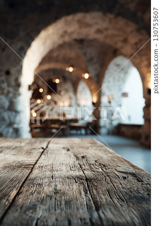 Rustic Mediterranean stone interior with wooden table and warm vintage lighting 130753607