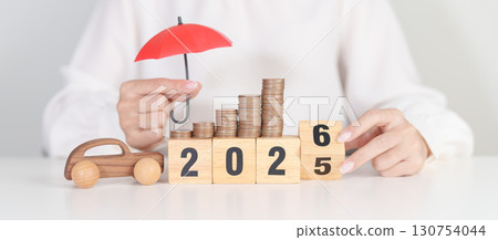 2025 end year to Happy New Year 2026 with red umbrella over money stack. car Insurance, Financial, vehicle Repair and Maintenance, Automobile Tax. Money Saving and New Year concept 130754044