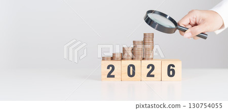 Happy New Year 2026 with  coins money stack growing with magnifier glass. Money saving, Inflation, tax, cash flow, Job search, hiring and research development concepts 130754055