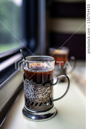 Close up tea glass holder with spoon on train table by window. Travel drink onboard classic service 130754410