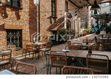 Outdoor dining area with string lights and rustic architecture in a cozy courtyard on a sunny day Outdoor dining area with string lights and rustic architecture in a cozy courtyard on a sunny day 130755068