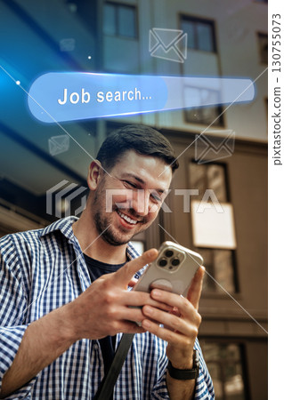Man engaged in job search on smartphone while standing outside a modern building during the day 130755073