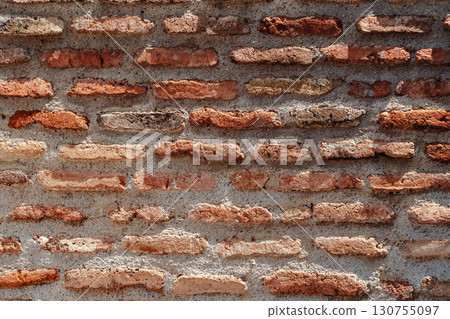 Brick wall with earthy tones showing texture and craftsmanship in a rustic setting 130755097