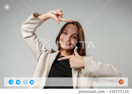 Woman gesturing with fingers in creative framing pose in studio setting during daytime Woman gesturing with fingers in creative framing pose in studio setting during daytime 130755116