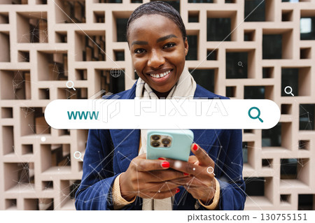 Young woman smiling while using smartphone in front of modern architectural background in urban setting during daytime 130755151