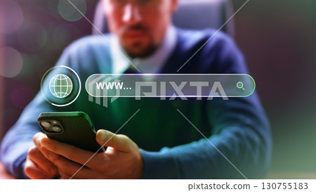 Man browses the internet on a smartphone while seated in an office environment focusing on online resources Man browses the internet on a smartphone while seated in an office environment focusing on online resources 130755183