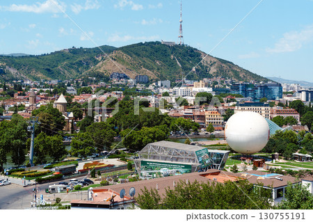 View of Tbilisi with scenic landscape showcasing hills, modern architecture, and urban life on a bright sunny day 130755191