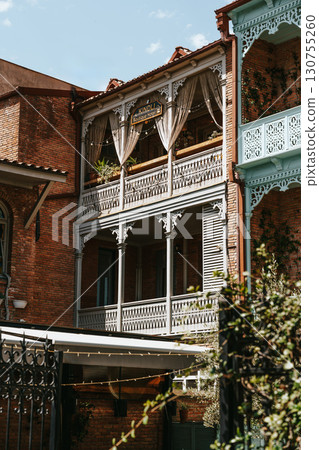 Historic wooden balcony in Tbilisi with intricate designs and nature elements on a sunny day Historic wooden balcony in Tbilisi with intricate designs and nature elements on a sunny day 130755260