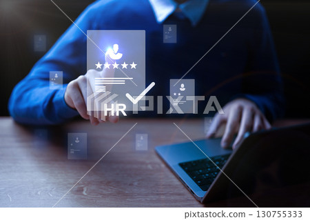 Human resources professional analyzing candidate profiles through a laptop at an office setting during the evening 130755333